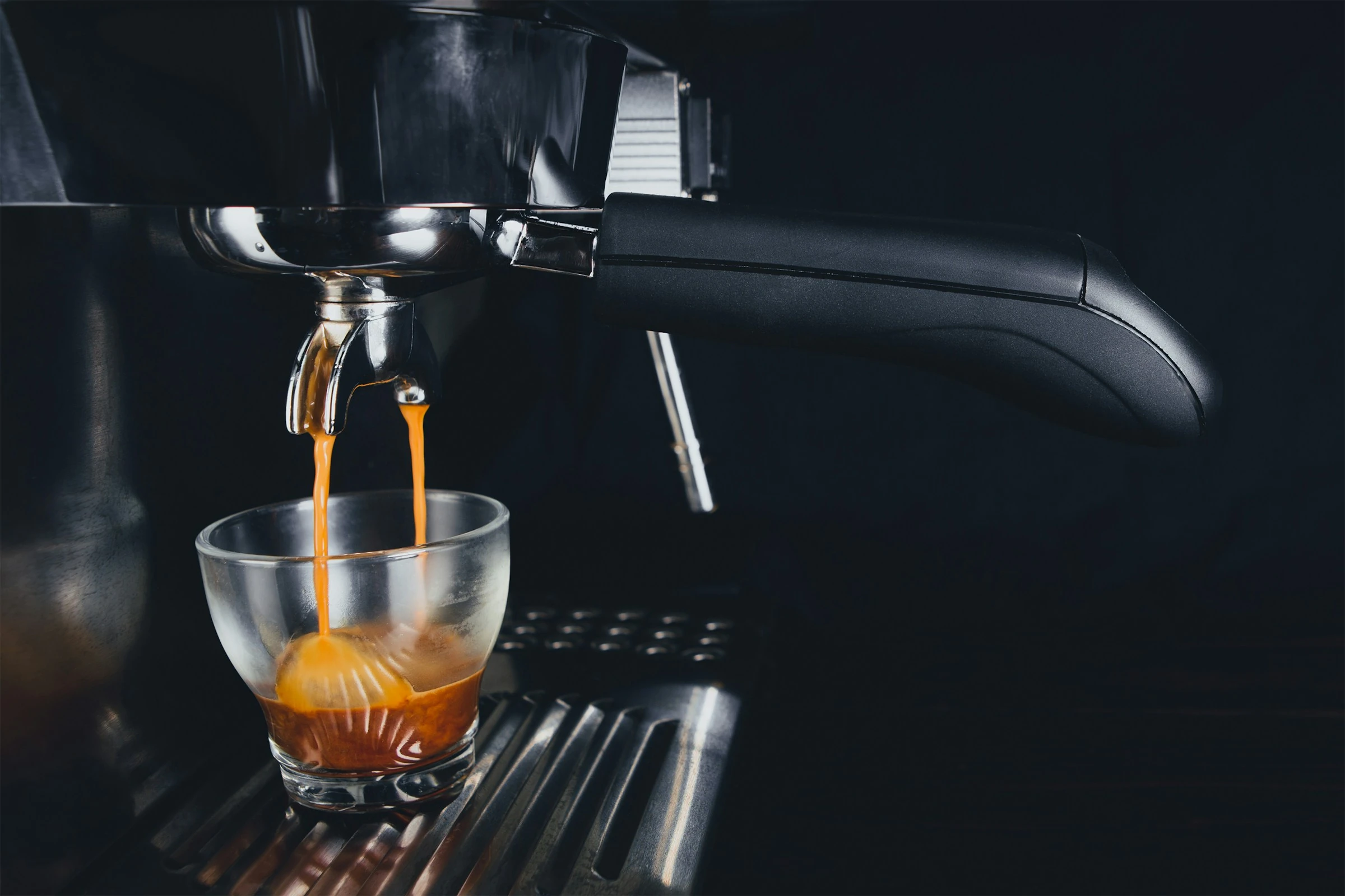 Two streams of espresso falling from a portafilter into a clear glass
